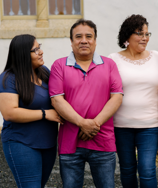 Latina daughter looking at her smiling father, her mother grinning to the side